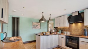 Une cuisine moderne avec un parquet en bois disposé en chevrons, un îlot central et un four encastré.