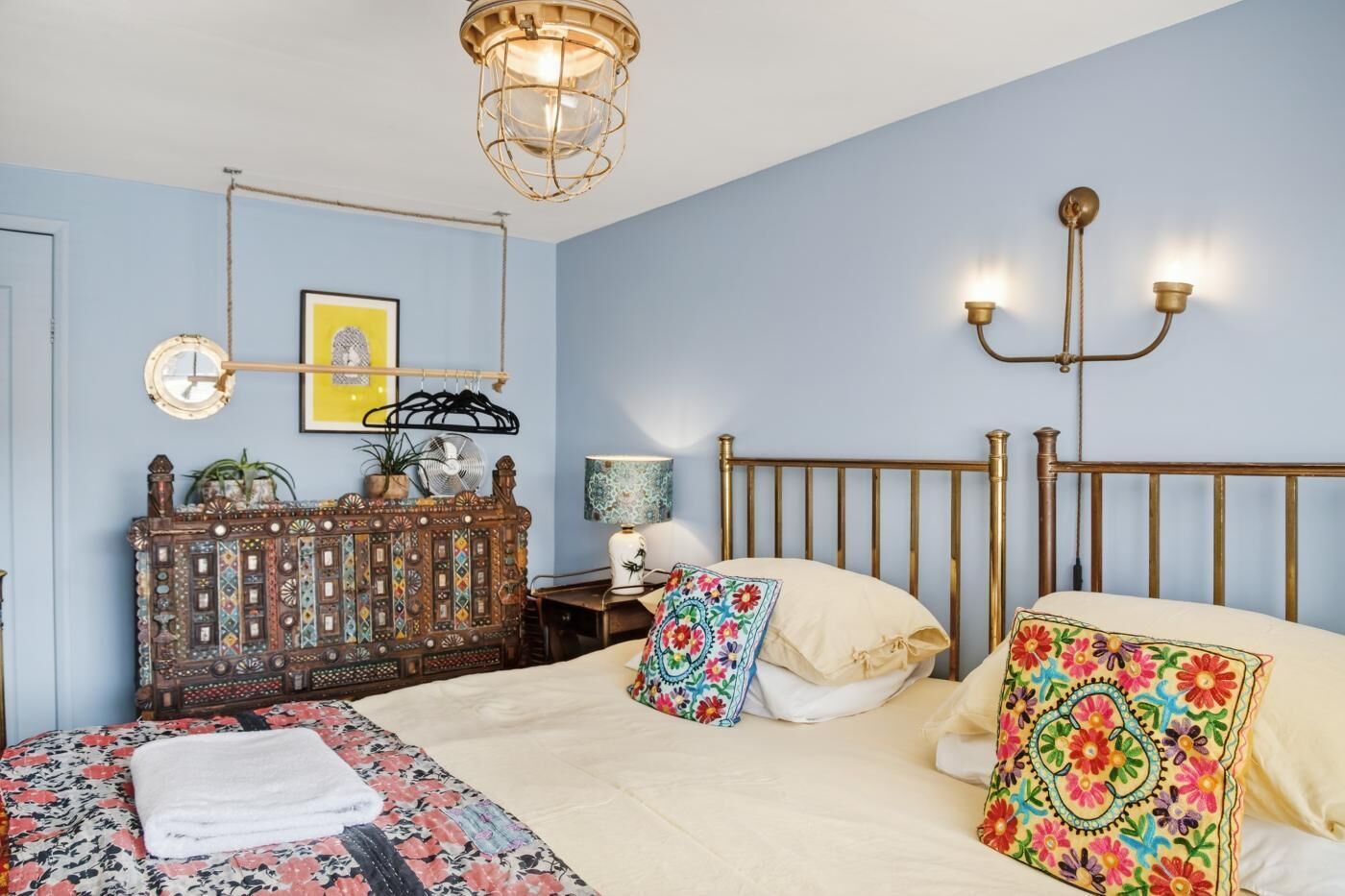 Camera da letto con un letto, comodino, lampada, opere d'arte a parete e una testiera decorativa.