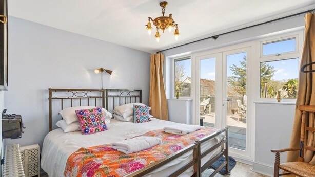 Une chambre à coucher avec un lit, un lustre, une fenêtre avec des rideaux et une vue sur l’extérieur.
