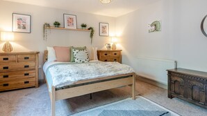 Een slaapkamer met een bed, nachtkastjes, een kaptafel en decoratieve wandkunst.