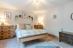 Ein Schlafzimmer mit einem Bett, Nachttischen, einer Kommode und Wandbildern.