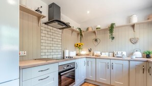 Een moderne keuken met een tegelwand van baksteen, roestvrijstalen apparatuur en lichtkleurige kastjes.