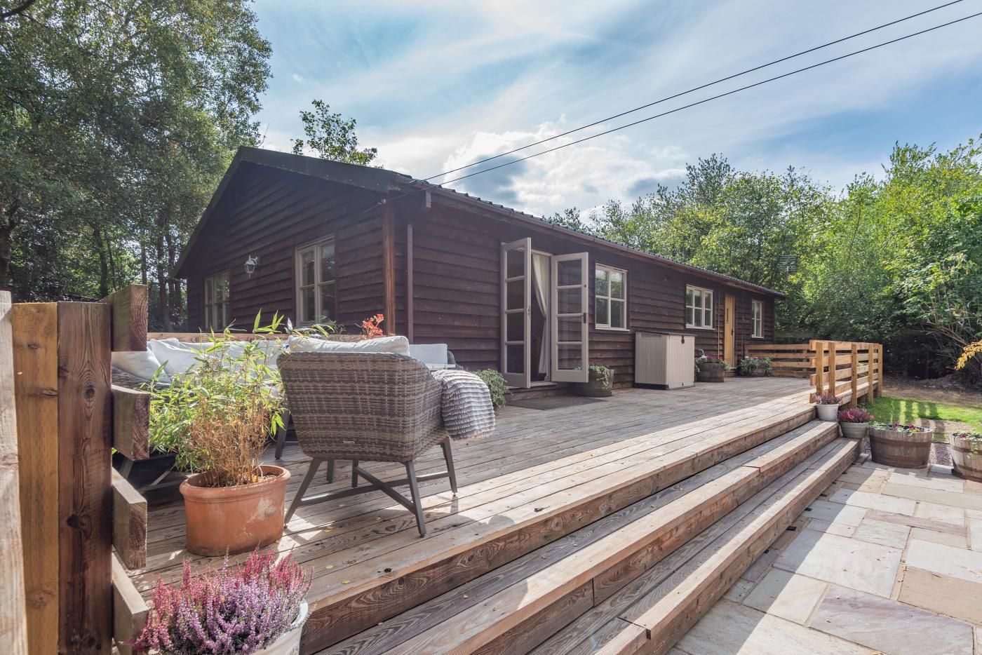 Une cabane en bois avec une terrasse, une chaise et des plantes en pot.