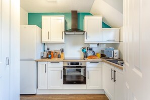 A compact kitchen with white cabinets, a built-in oven, a toaster, and a microwave.