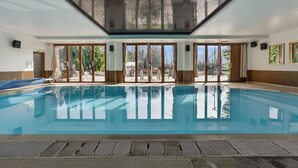 Ein Innenpool mit großen Glaswänden, einer Decke mit Oberlichtern und Blick ins Freie.