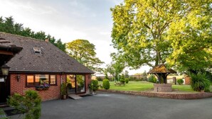 A brick building with a covered entrance, a paved driveway, and a small garden area with a gazebo. - 2 Bed in Alkham (oc-p34786) (Swingfield)