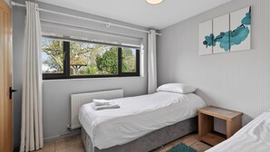 A bedroom with a bed, a bedside table, a radiator, a window with curtains, and a view of trees. - 2 Bed in Alkham (oc-p34786) (Swingfield)