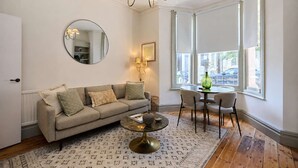 Een woonkamer met een bank, salontafel en een eethoek met stoelen en een tafel.