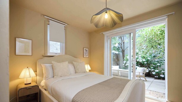 Een slaapkamer met een bed, bedlampen, een raam en uitzicht op de omgeving.