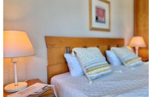A hotel room with a bed, two bedside lamps, a wooden headboard, and a framed picture on the wall. - Ferienwohnung mit Fitness und Freizeitangeboten (Sellin)