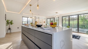A modern kitchen with a large island, pendant lighting, and large windows. - 2 Bed in St. Minver (oc-g34708) (Saint Minver)