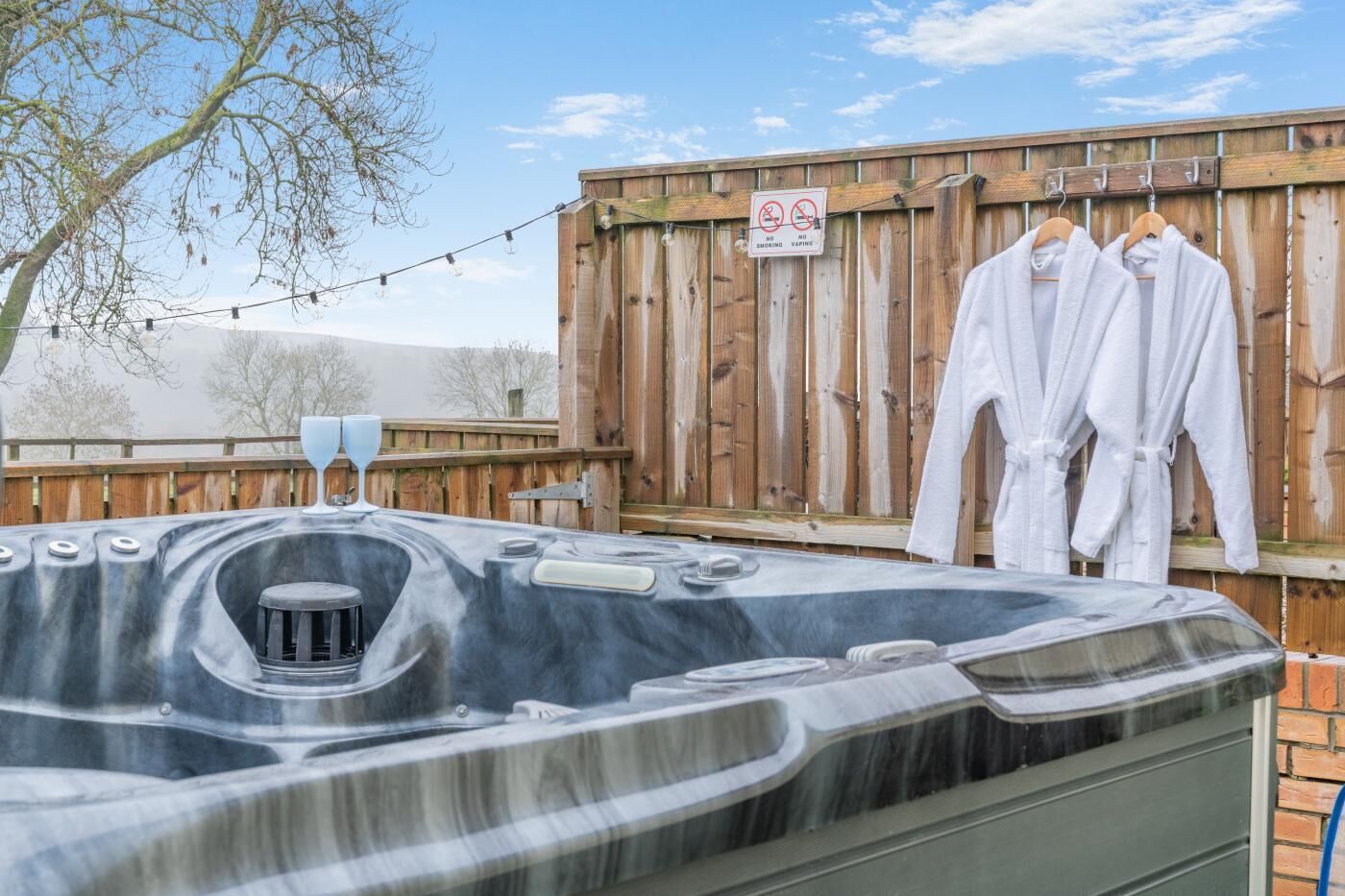 A hot tub with a wooden fence and a no smoking/vaping sign in the background.