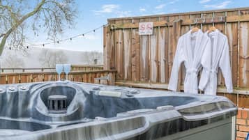 A hot tub with a wooden fence and a no smoking/vaping sign in the background.