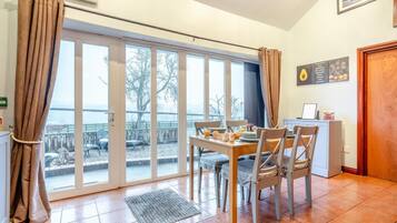 A dining area with a table set for two, a view through large glass doors, and a kitchen area with a counter and cabinets.