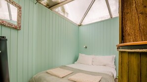 Een kamer met een bed, een spiegel en een houten constructie.
