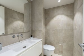 Uma casa de banho moderna com banheira, sanita e um espelho grande.