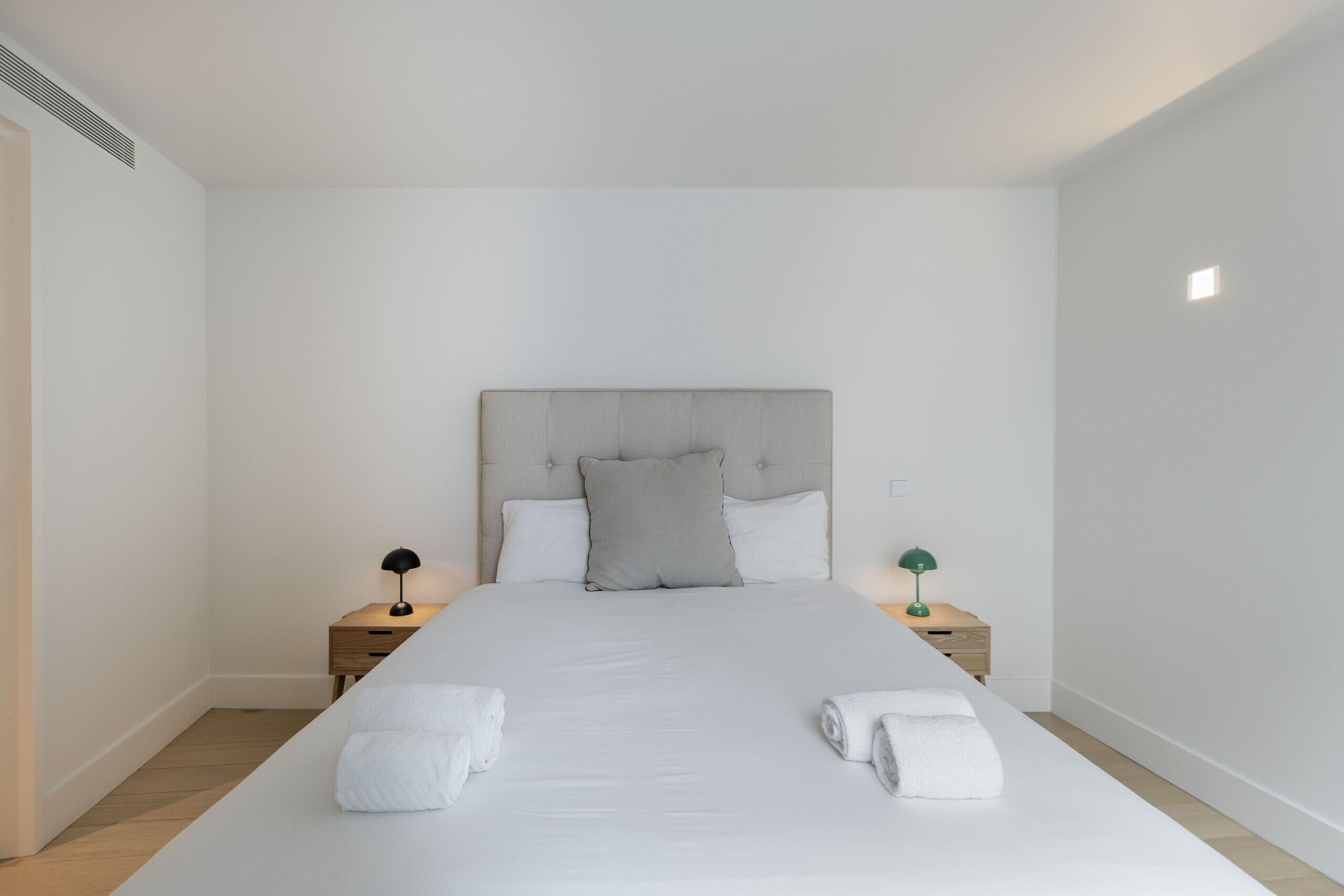 Un dormitorio con una cama grande, dos mesitas de noche y un cabecero.