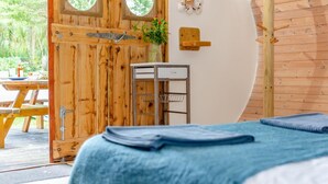 Ein Zimmer aus Holz mit einem Bett, einem kleinen Tisch und einem an der Wand befestigten Regal.
