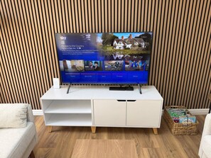A flat-screen TV on a white entertainment unit with a wooden slat wall behind it. - 3 Bed Lodge Dog-friendly Garden Ev Nr M1 Junc 23 (Loughborough)