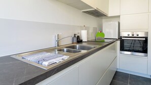 Eine moderne Küche mit Spüle aus Edelstahl, Backofen und weißen Schränken.