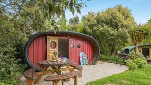 Ett unikt hus med en cirkelformad design, ett picknickbord och en liten trädgårdsyta.