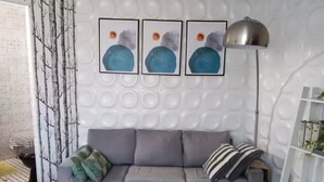 A modern living room with a grey sofa, a white coffee table, and a wall with circular patterns. - 4. Moderno Departamento Entero Estilo Minimalista - CUARTO PISO (Breña)