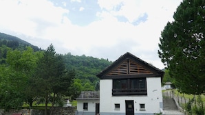 Ein zweistöckiges Gebäude mit weißer Fassade, schwarzem Dach und einer kleinen Veranda.