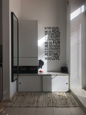 A modern interior with a white console, a mirror, and a wall with motivational text. - KlimasHouse - Bright City Loft (Vilnius)