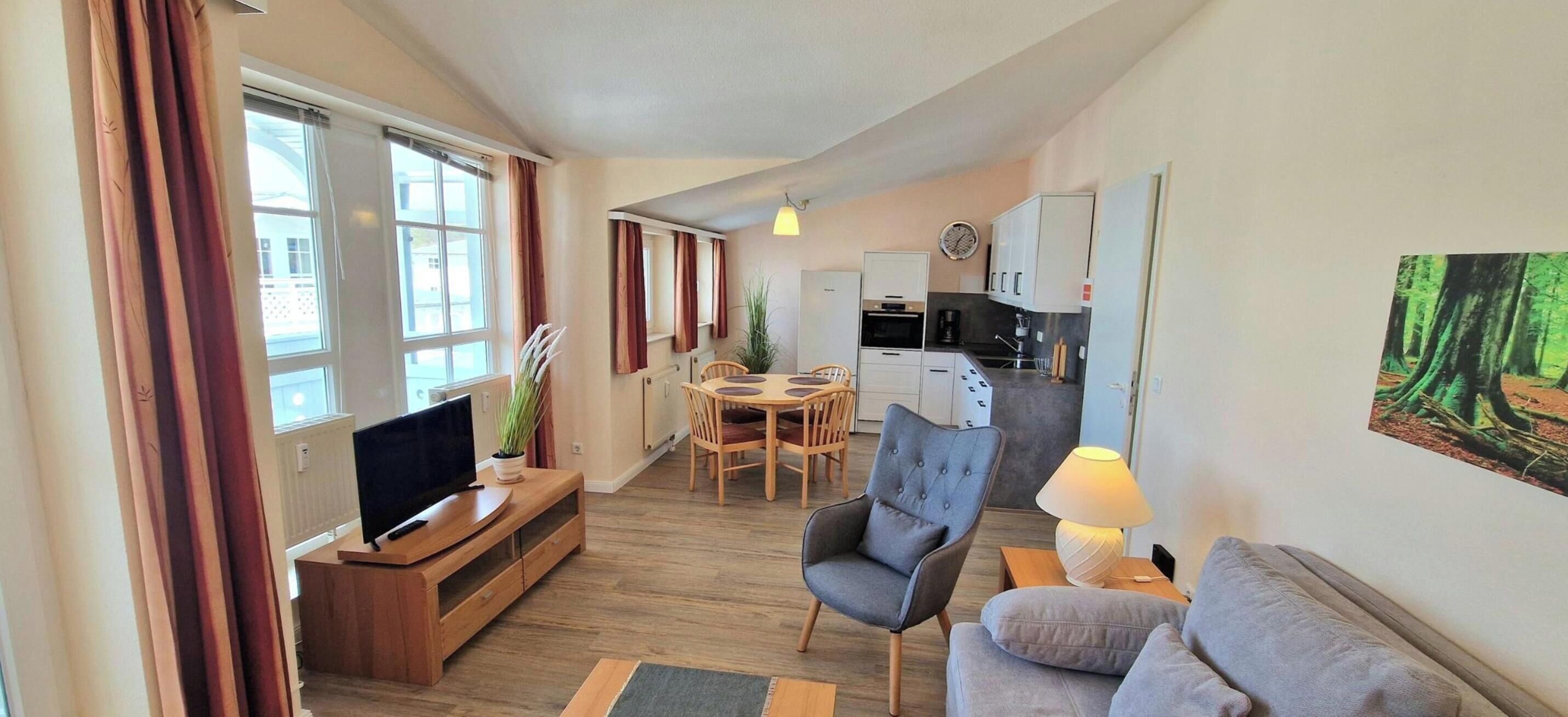 Ein kompakter Wohnbereich mit Fernseher, Sofa, Esstisch und Küchenzeile.