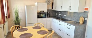 Eine kleine Küche mit Kühlschrank, Backofen, Spüle und weißen Schränken.