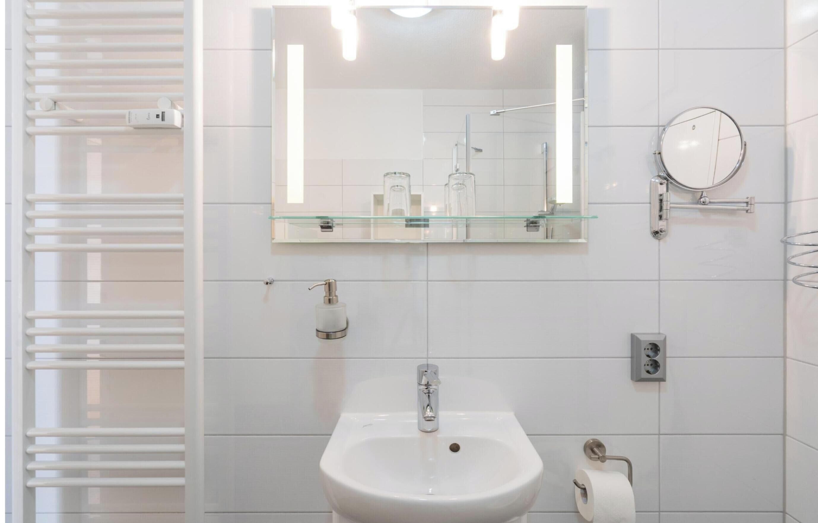 A modern bathroom with a glass shelf, a sink, a mirror, and a towel rack.