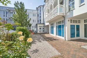 A hotel with a gravel pathway, a rose garden, and a building with a balcony. - Ferienwohnung mit Moblierten Balkon in Sellin (Sellin)
