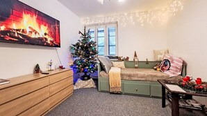 A cozy room with a bed, a small Christmas tree, a TV, and a desk with a lamp. - Cosy apartment for 4 people with WIFI and TV (Jilemnice)