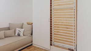 A room with a white wardrobe, a beige sofa, and a window with horizontal blinds. - Cosy apartment for 4 people with WIFI and TV (Jilemnice)