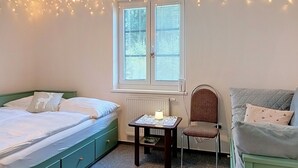 A bedroom with a bed, a chair, a table with a lamp, and string lights. - Cosy apartment for 4 people with WIFI and TV (Jilemnice)