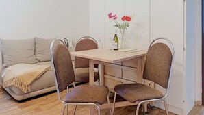 A dining area with a table, four chairs, a sofa, and a vase with flowers. - Cosy apartment for 4 people with WIFI and TV (Jilemnice)