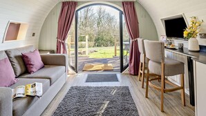 Un intérieur chaleureux avec un canapé, un coin repas et une grande fenêtre agrémentée de rideaux.