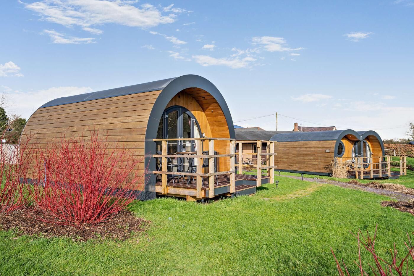 Two wooden cabins with arched roofs and wooden decks.