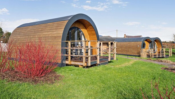 Deux cabanes en bois dotées de toits en arc et de terrasses en bois.