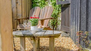 Un tavolo di legno con una pianta in vaso, pane, due bicchieri e una sedia, il tutto in un giardino.