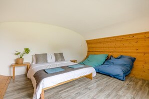 Ein Schlafzimmer mit einem Bett, einem Nachttisch, einer Topfpflanze und einem Holz-Kopfteil.