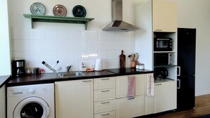 Una cuina compacta amb rentadora, microones i forn integrat.