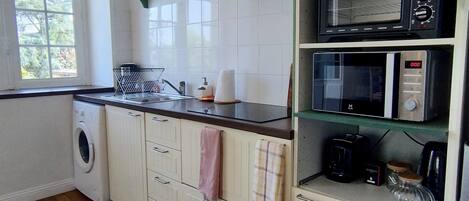 A kitchen with a washing machine, a microwave, and a coffee maker.