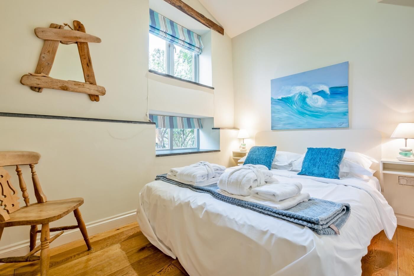A bedroom with a bed, a chair, a window, and a painting.