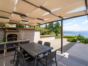 Un patio al aire libre con chimenea de piedra, una mesa con sillas y vistas a un lago y al skyline de la ciudad.