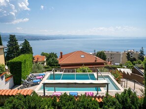 Piscina en la azotea con vista a un lago, rodeada de edificios y vegetación.