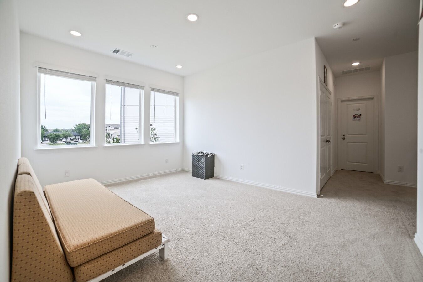 A spacious room with large windows, a bench, and a door leading to another area.