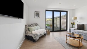 A modern living room with a sofa, a coffee table, a TV mounted on the wall, and a sliding glass door leading to an outdoor area. - 1 Bed in Bontuchel (oc-t34921) (Bontuchel)