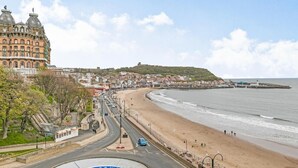 Une ville côtière qui abrite un bâtiment historique remarquable, une plage et une route menant à un rond-point.