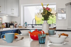 Una encimera de cocina con un hervidor rojo, un vaso azul y un cuenco blanco.